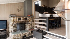 A modern kitchen with a stone fireplace, wooden cabinets, and a dining area with a table and chairs.