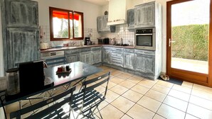A kitchen with a dining table, chairs, cabinets, a microwave, and a stove.