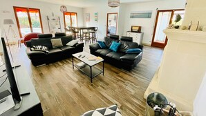 A spacious living area with a sofa set, a coffee table, and a dining table.
