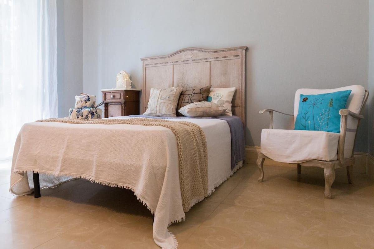 A bedroom with a bed, a nightstand, a chair, and a window.