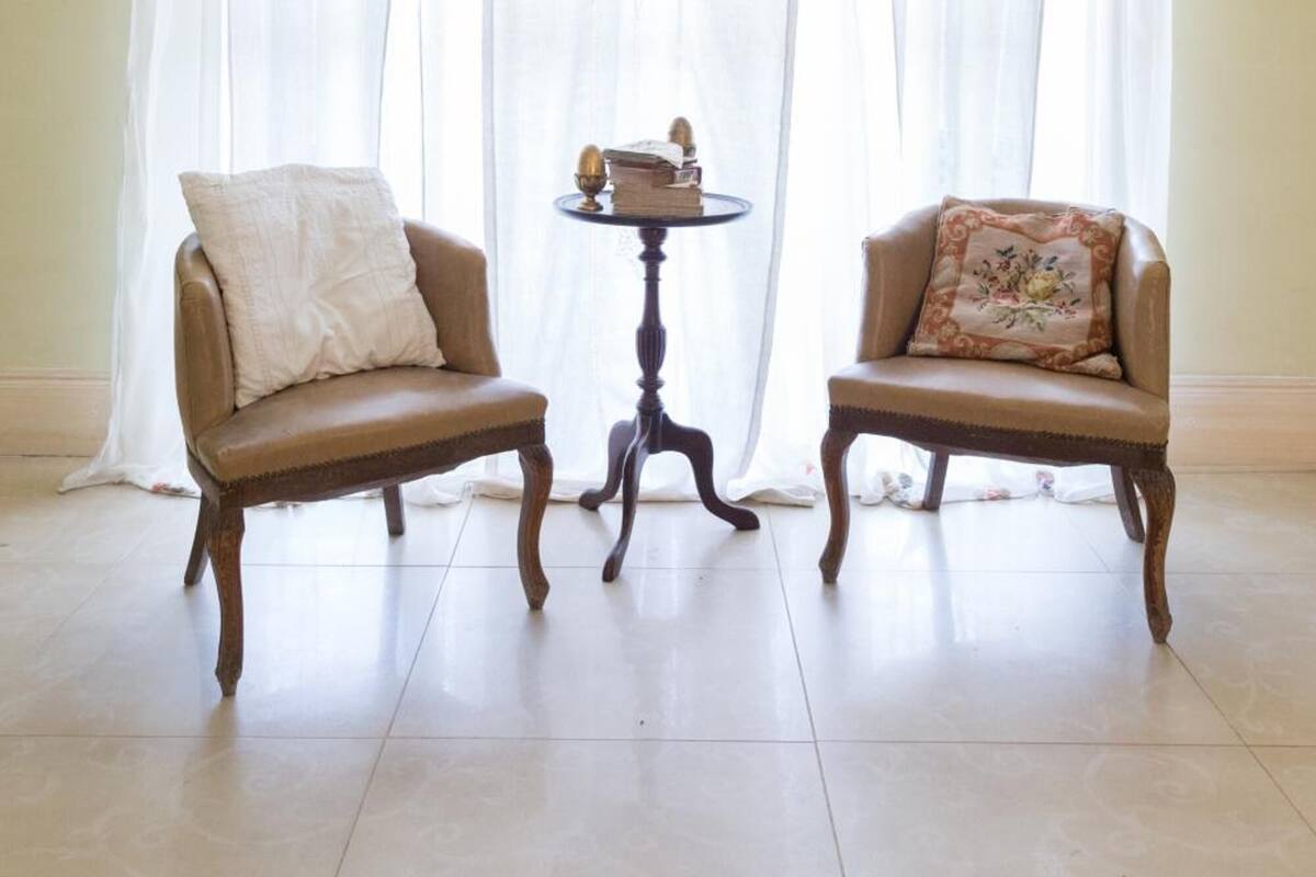 A room with two wooden chairs, a small round table, and a decorative curtain.