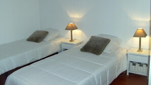 Une chambre d’hôtel avec deux lits simples, chacun étant équipé d’un oreiller et d’une table de chevet avec une lampe.