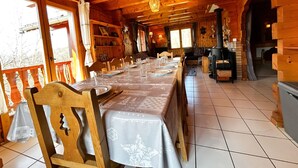 A wooden cabin with a long dining table set for a meal, wooden chairs, and a fireplace. - Chalet for up to 16 guests in Bernex, pets welcome (Bernex)
