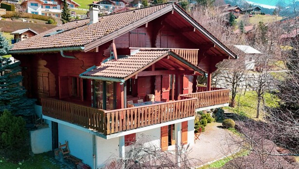 A two-story wooden chalet with a balcony, surrounded by a mountainous landscape. - Chalet for up to 16 guests in Bernex, pets welcome (Bernex)