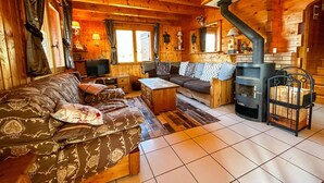 A cozy log cabin interior with a sofa, a small table, a fireplace, and a television. - Chalet for up to 16 guests in Bernex, pets welcome (Bernex)