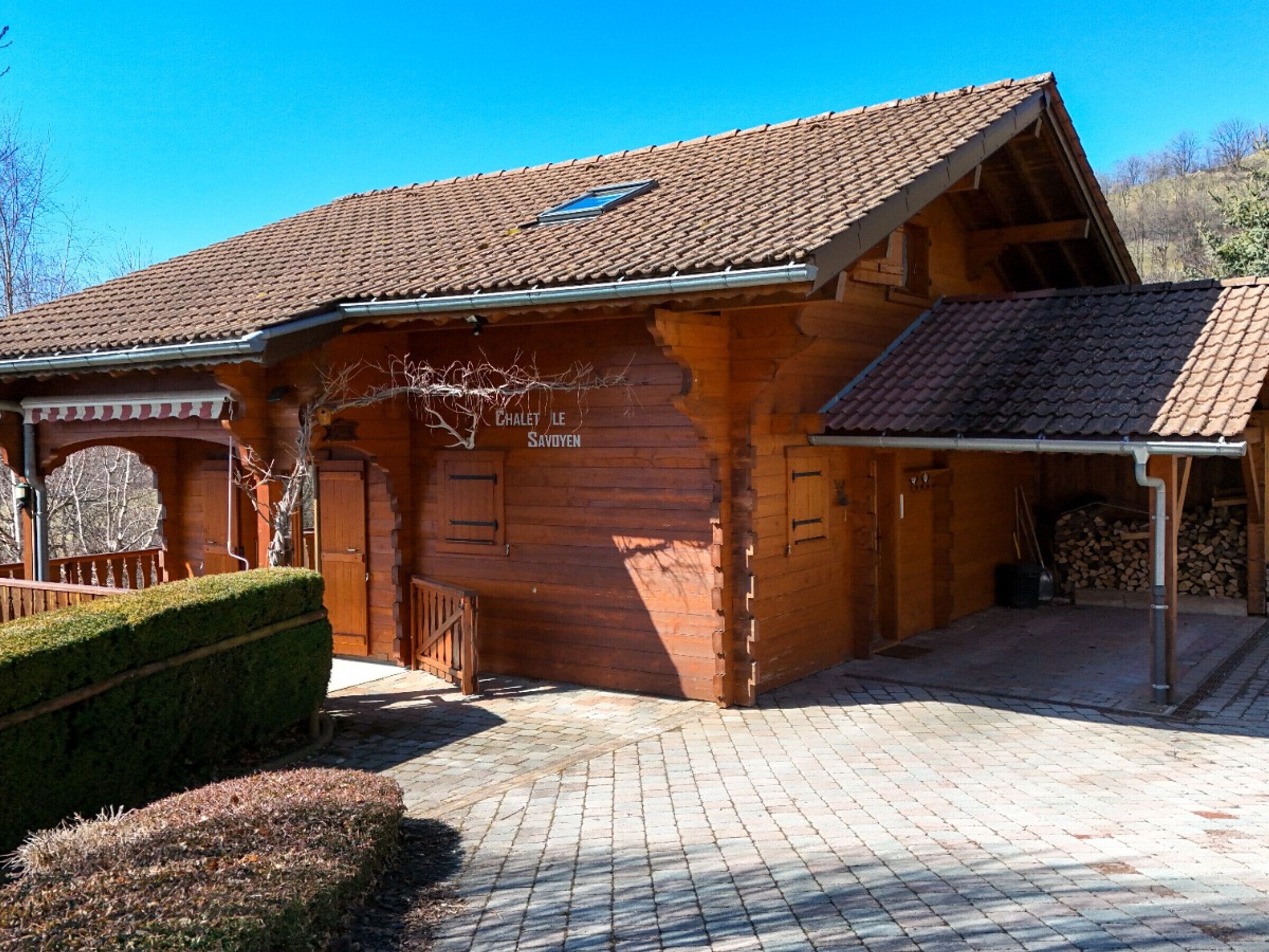 A wooden chalet with a tiled roof, a covered porch, and a chimney.