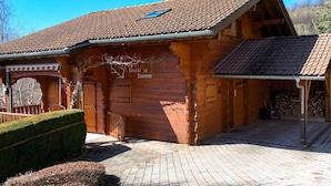 A wooden chalet with a tiled roof, a covered porch, and a chimney. - Chalet for up to 16 guests in Bernex, pets welcome (Bernex)