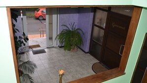 A hotel lobby with a potted plant, a wooden bench, and a door labeled "Gourmet."