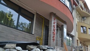 A building with a curved facade, a stone wall in front, and a sign that reads "Restroom".