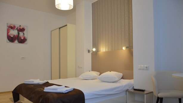 A modern hotel room with a neatly made bed, a chair, and a small table.