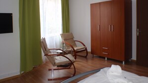 A room with a wooden wardrobe, two rocking chairs, and a bed.