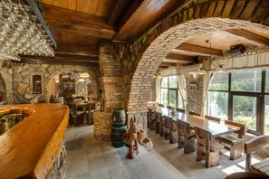 A rustic interior with stone walls, wooden beams, and a bar area with stools and a large wooden counter. - Luksuzne sobe Luce (Vrbnik)