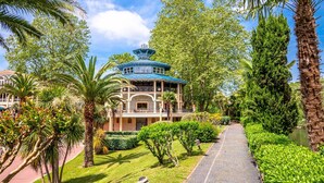 A traditional-style building with a blue roof, surrounded by lush greenery and palm trees.