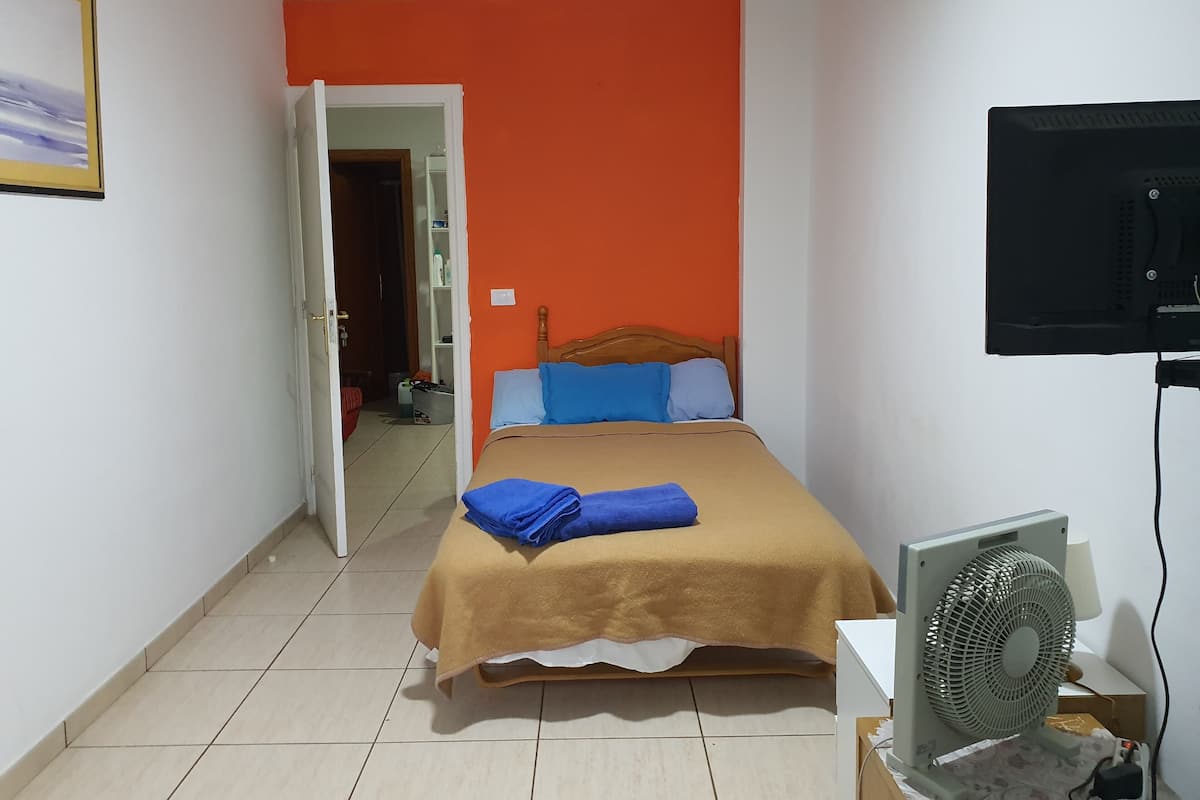 A room with a bed, a fan, and a TV.