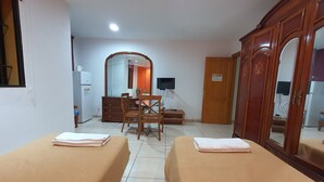 A hotel room with two beds, a wooden wardrobe, a desk with a chair, a mirror, and a television. - Doramas Private Rooms Shared Toilet (San Bartolomé de Tirajana)