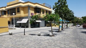 A paved outdoor area with bollards, a building with a yellow facade, and a tree. - Doramas Private Rooms Shared Toilet (San Bartolomé de Tirajana)