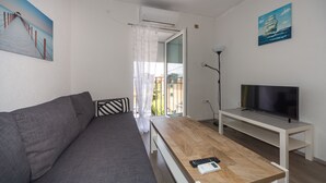 A modern living room with a grey sofa, a wooden coffee table, a flat-screen TV, and artwork on the walls. - Apartments Karolina (Opatija)