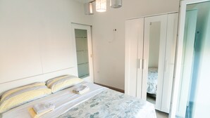 A bedroom with a bed, a wardrobe, and a sliding glass door. - Apartments Karolina (Opatija)