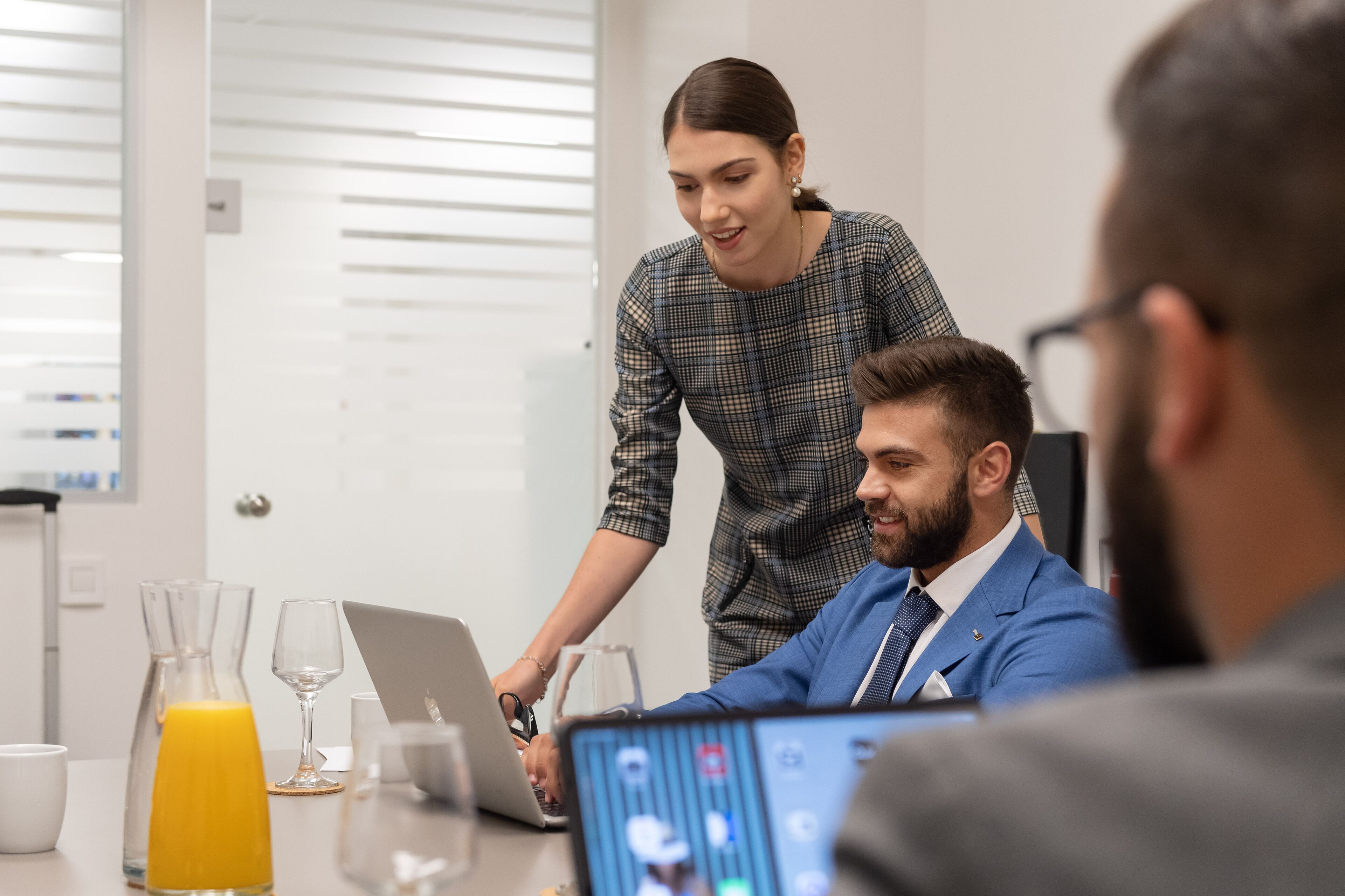 Riunione di lavoro in un ufficio moderno dagli interni bianchi, con un laptop e un bicchiere di succo d'arancia sul tavolo.