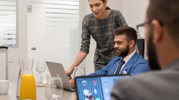 Riunione di lavoro in un ufficio moderno dagli interni bianchi, con un laptop e un bicchiere di succo d'arancia sul tavolo.