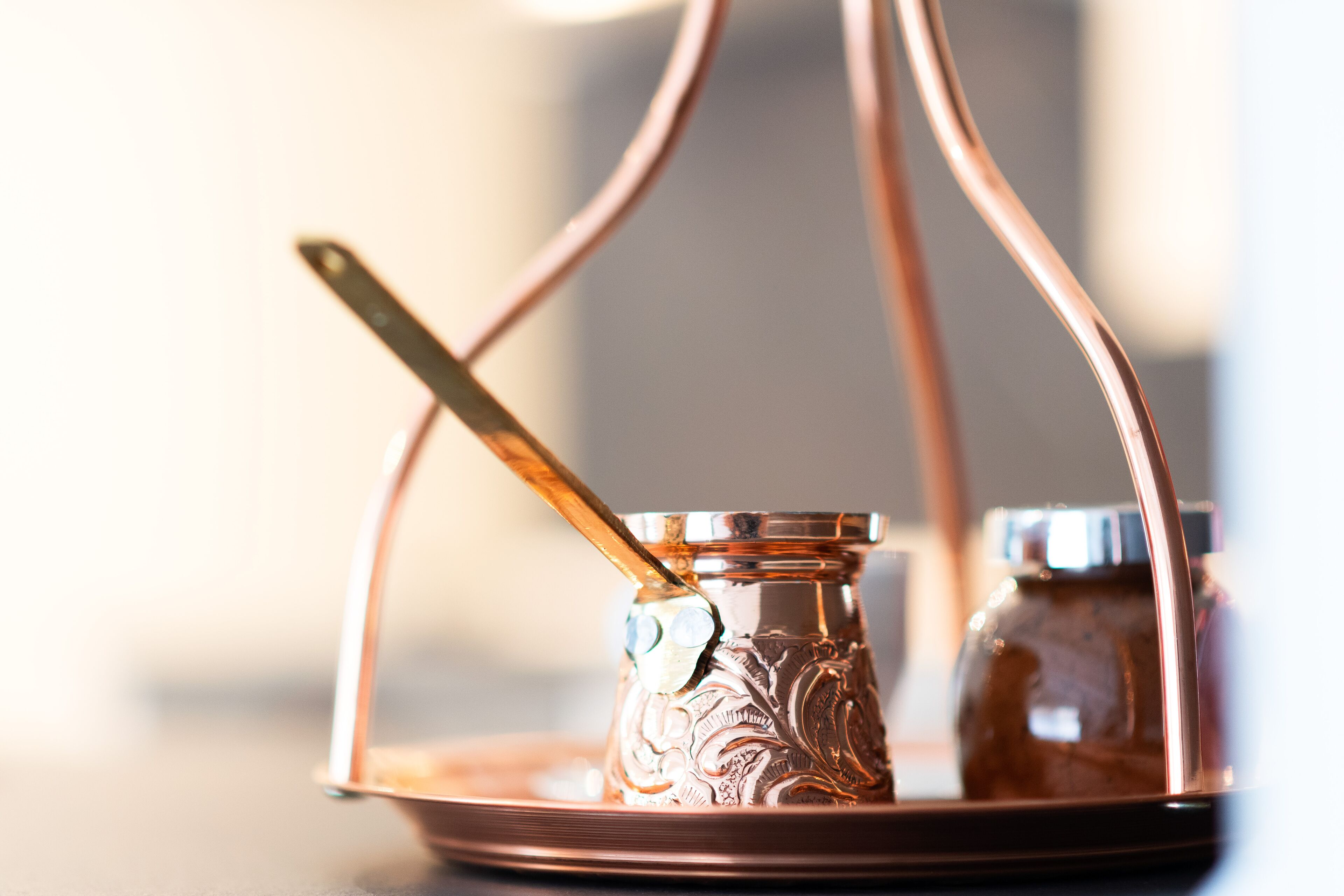 A copper tray with a glass container and a spoon.