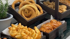 A bakery display with various baked goods including bread, croissants, and sesame seed rolls. - Thess Residences (Thessaloniki)