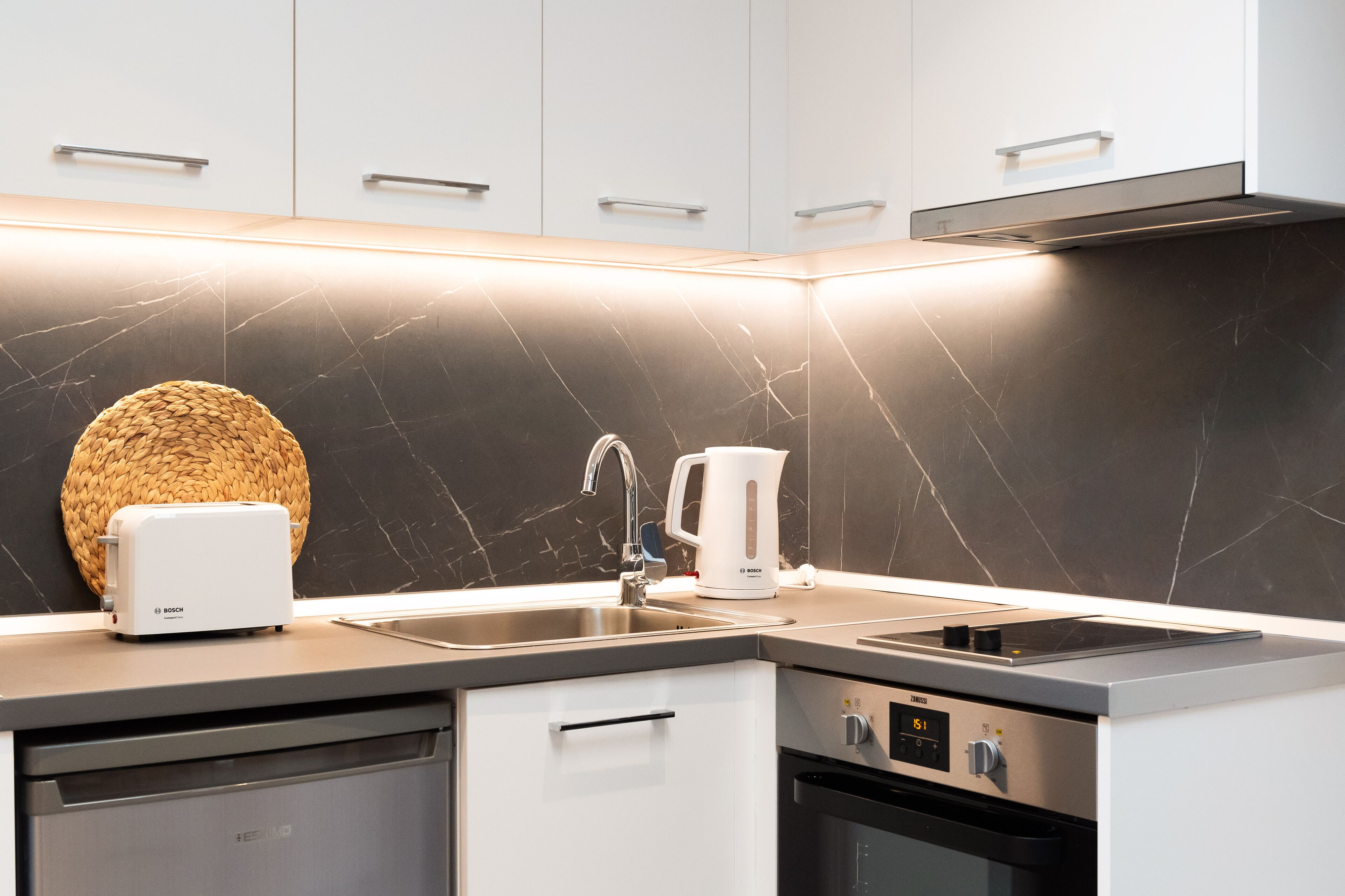 A modern kitchen with a Bosch toaster, a coffee maker, and a built-in oven.
