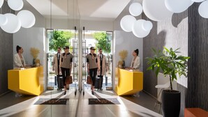 A modern hotel lobby with a glass partition, reception desks, and a large potted plant. - Thess Residences (Thessaloniki)