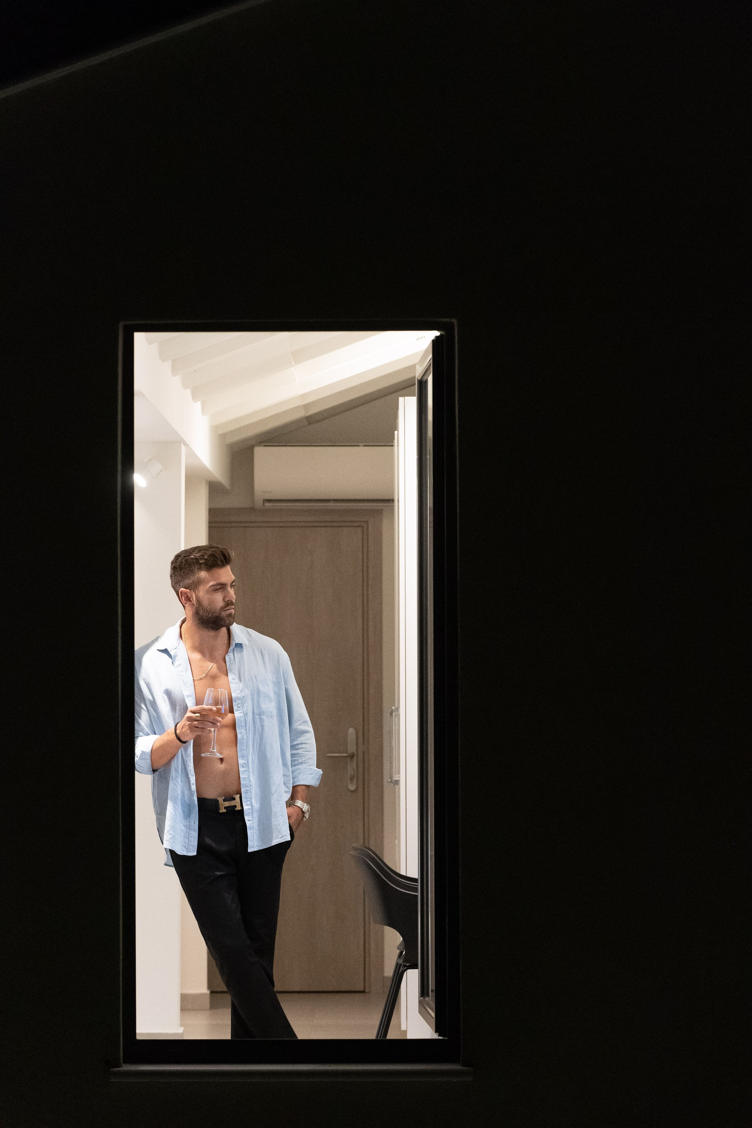 A man in a room with a door, a chair, and a light fixture on the ceiling.