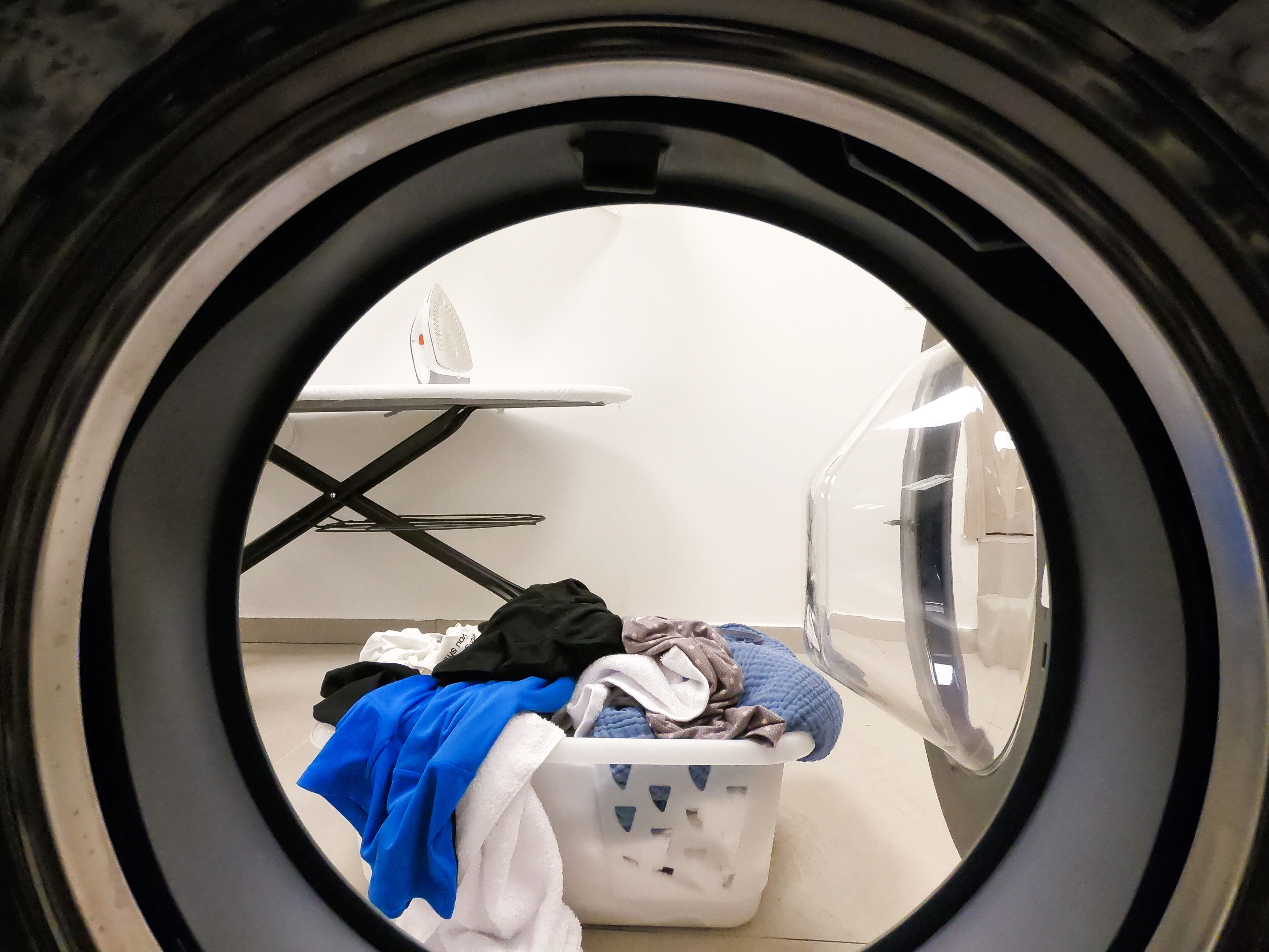 A laundry room with a washing machine, a drying rack, and a basket of clothes.