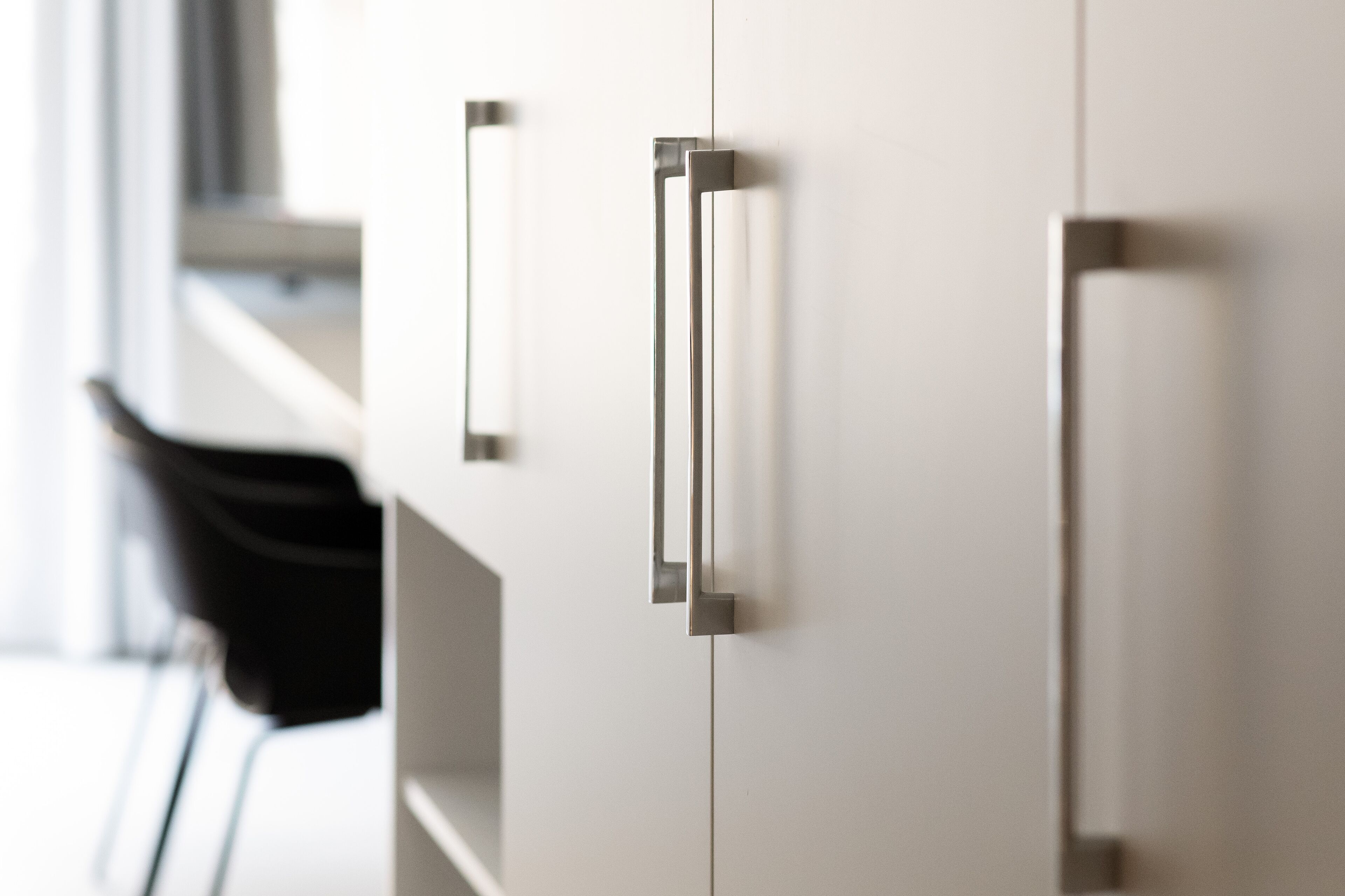 A modern kitchen with white cabinets and stainless steel handles.