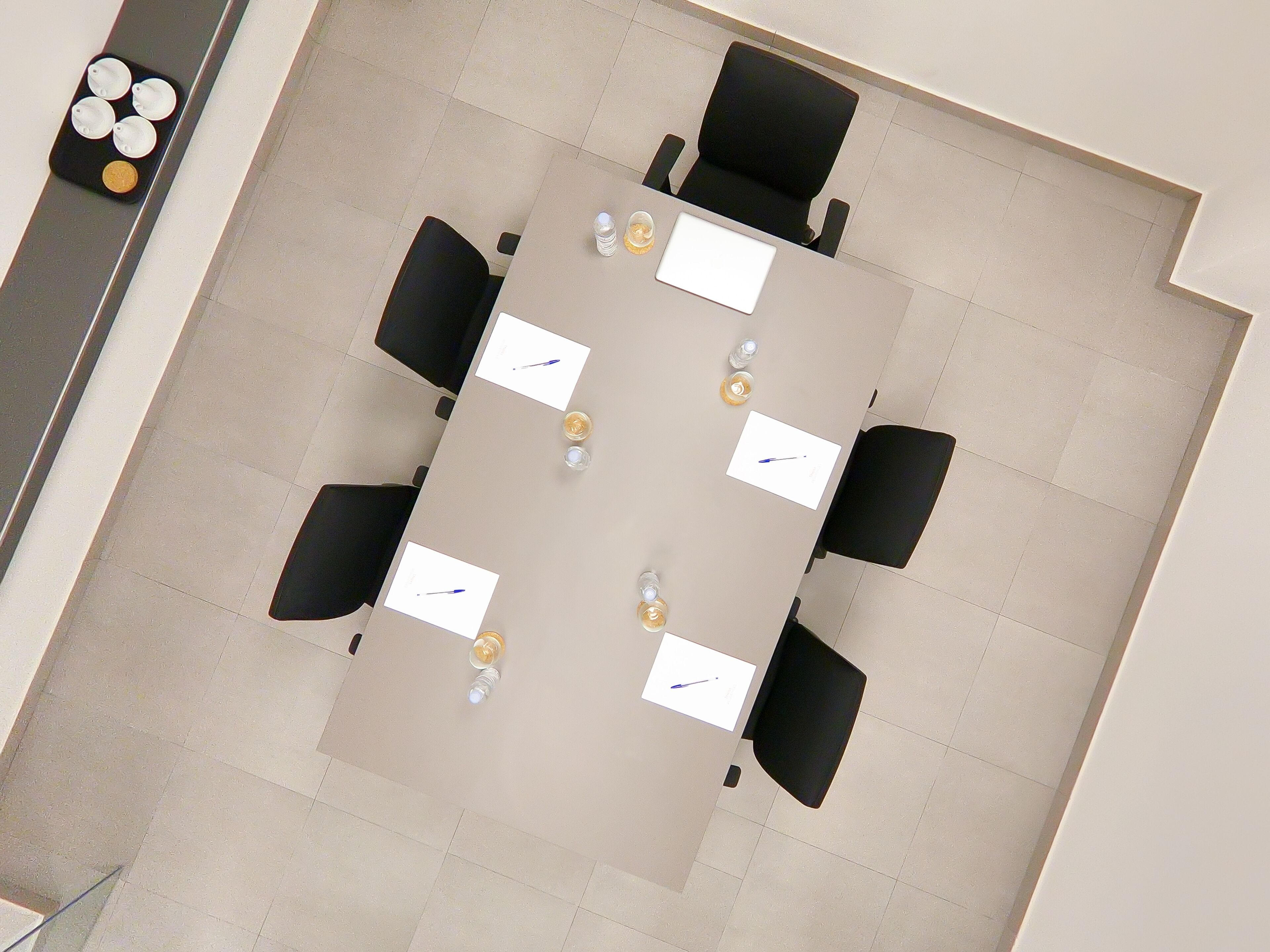 A conference room with a rectangular table, black chairs, and white nameplates.