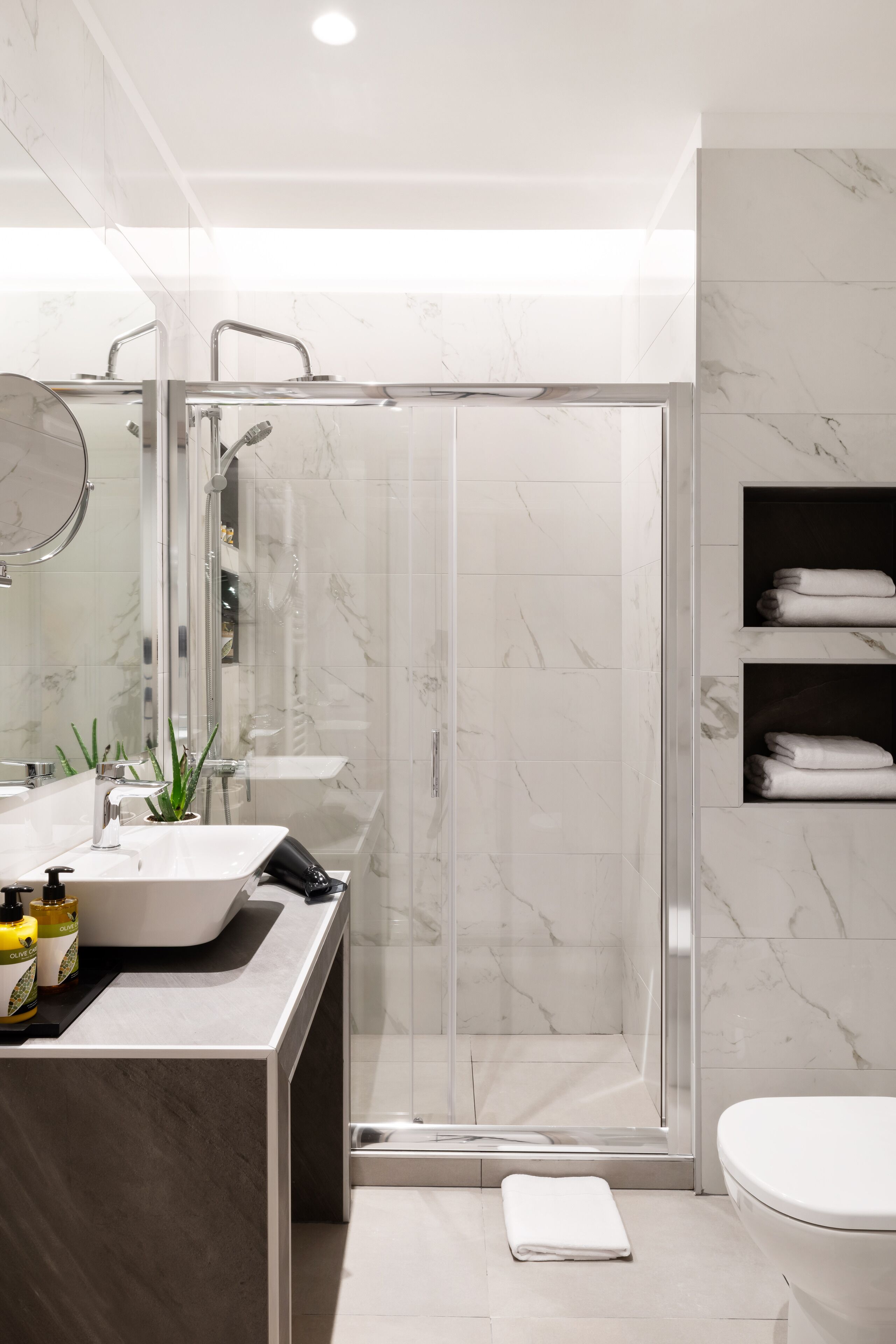 A modern bathroom with a glass-enclosed shower, a white sink, and a toilet.