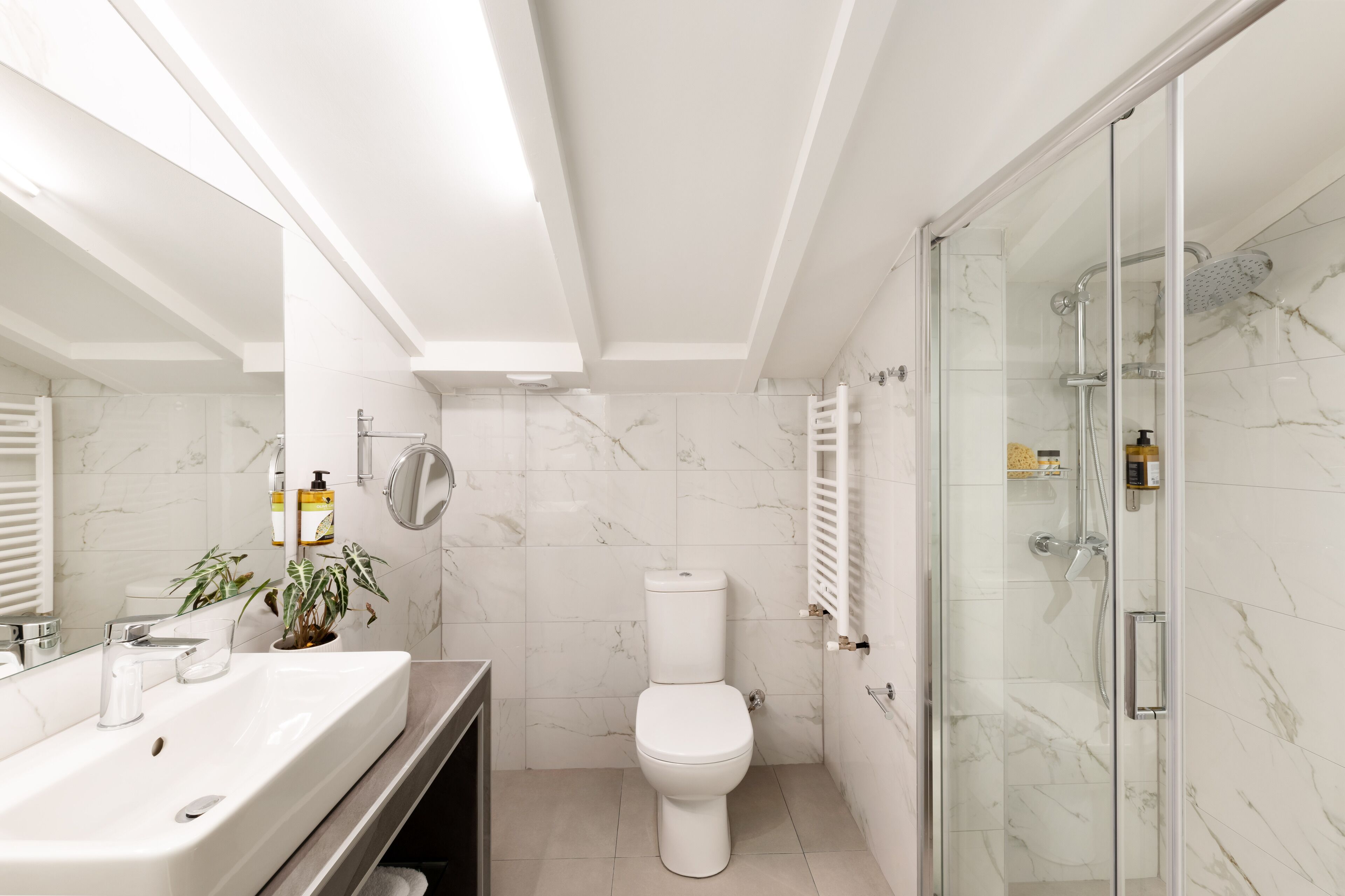 Une salle de bain moderne avec un lavabo blanc, des toilettes et une douche à parois de verre.