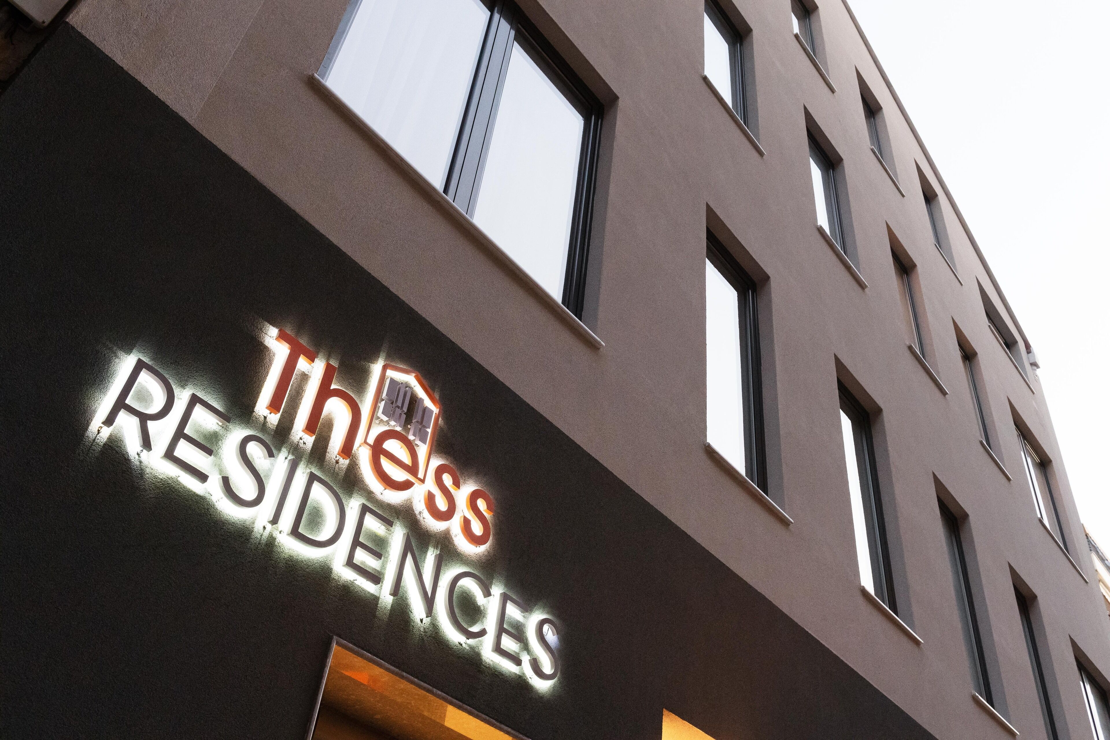 A building with a sign that reads "Thess Residences."