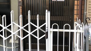 A gated entrance with a sign for Masaru House, a metal fence, and a utility pole.