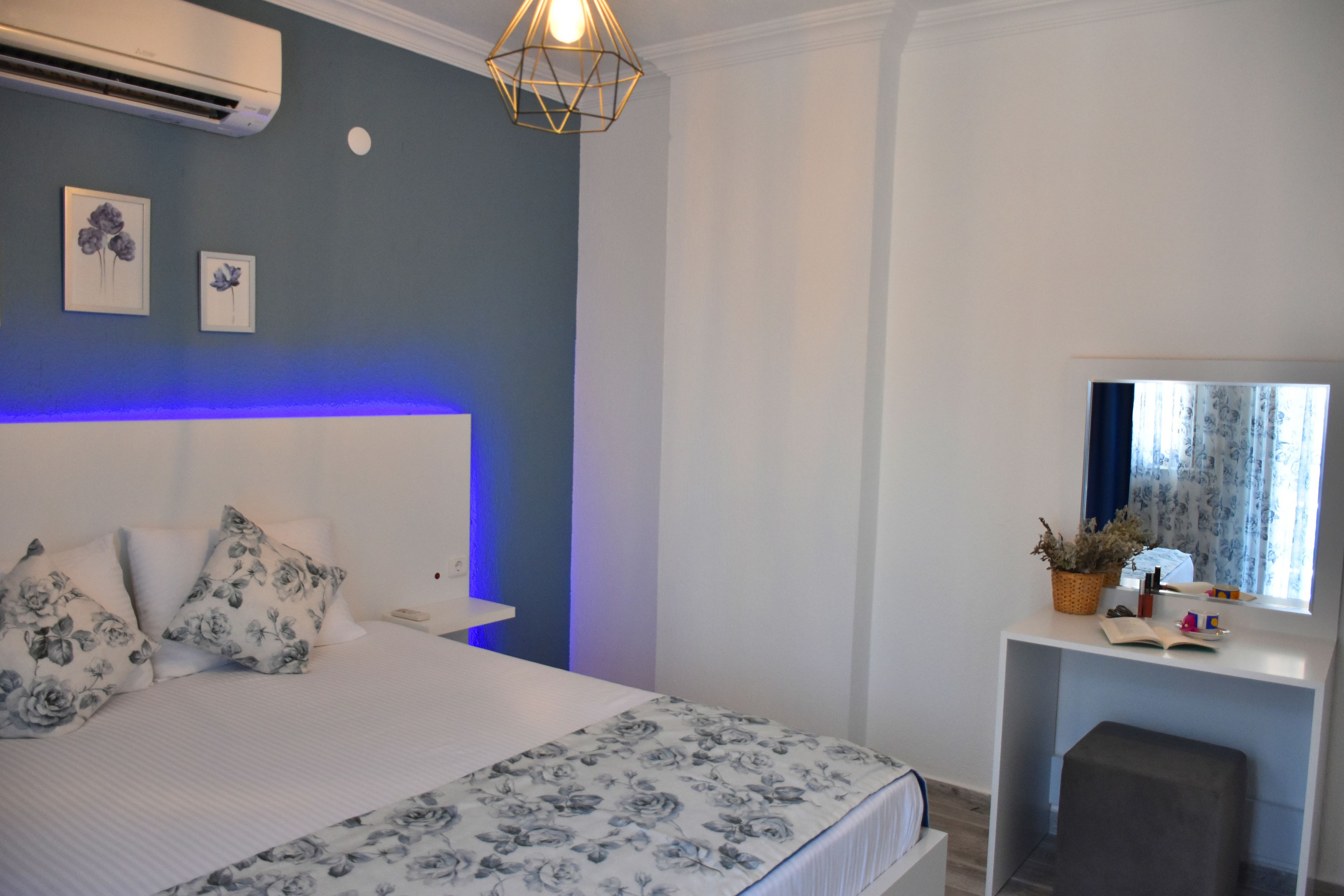 A bedroom with a bed, a bedside table, a mirror, and a window.