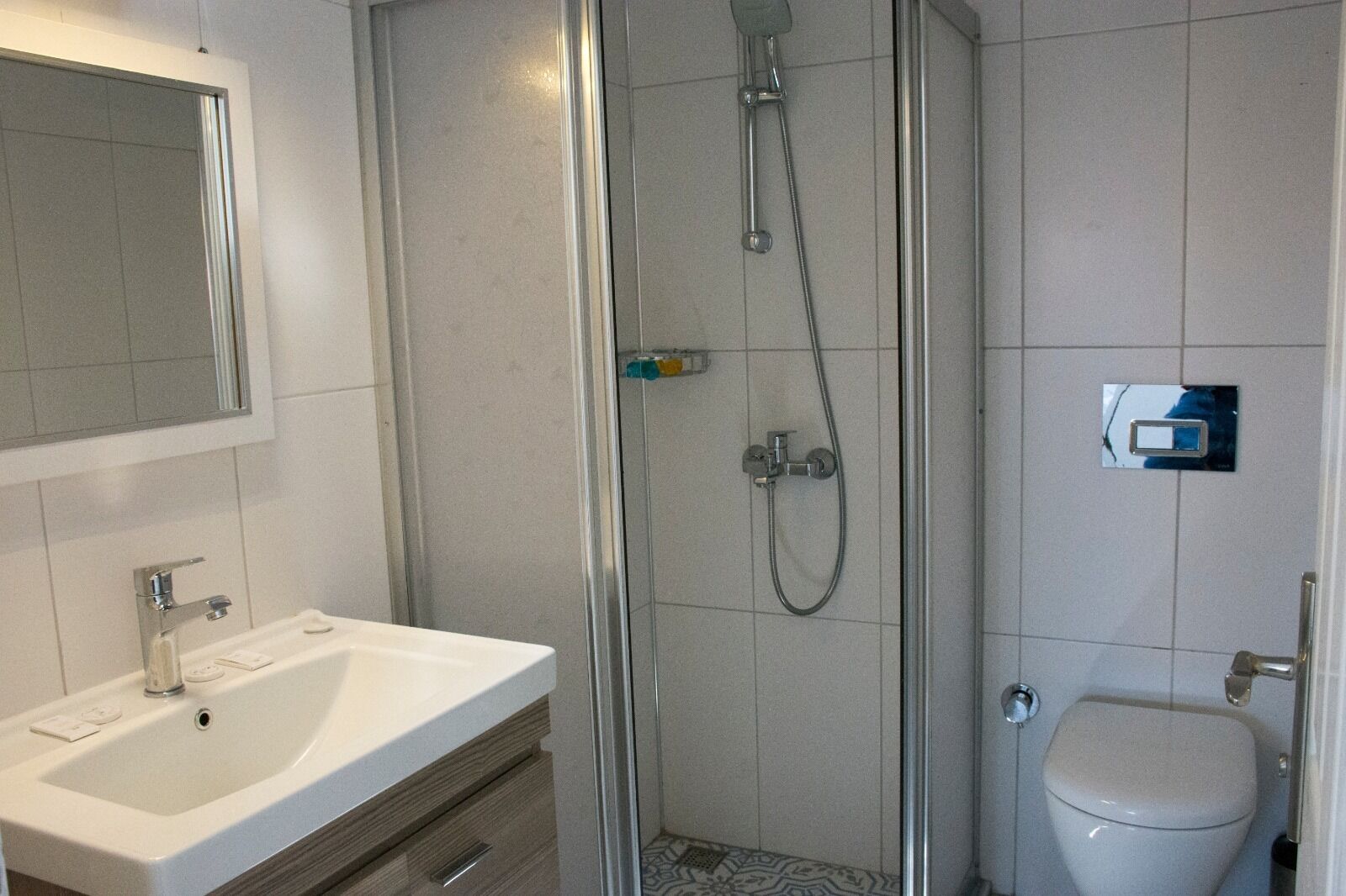 A modern bathroom with a glass-enclosed shower, a white sink, and a toilet.