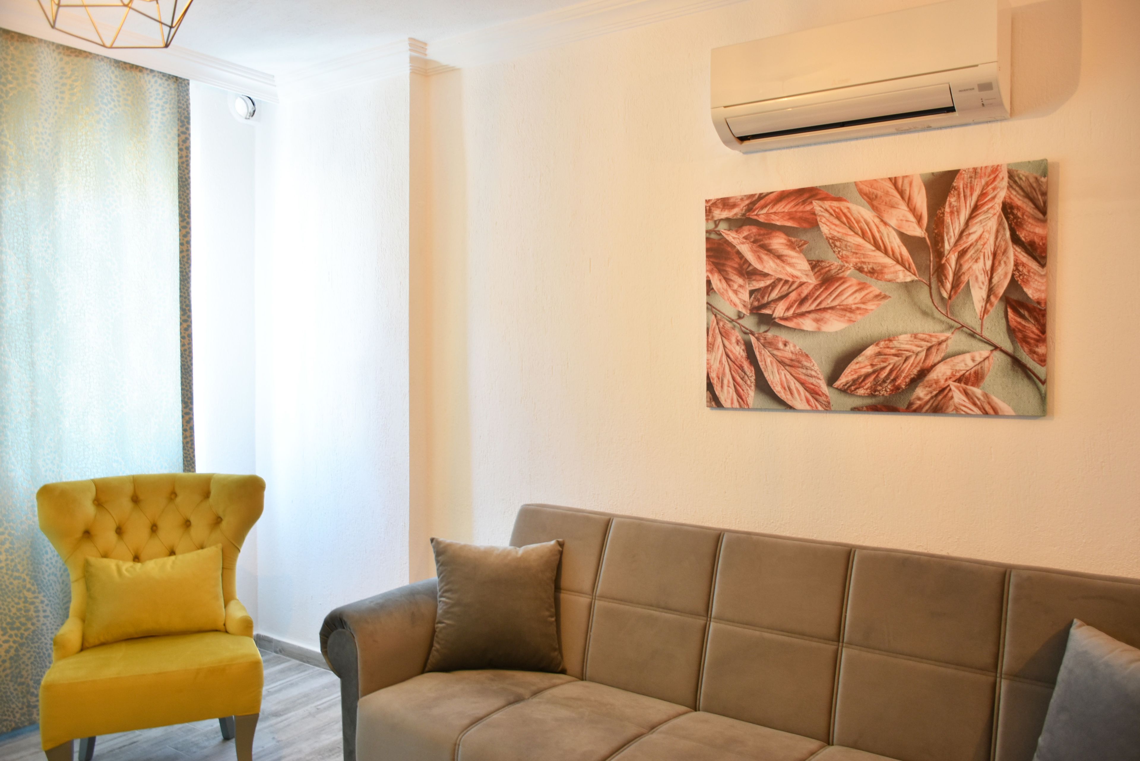 Ein Wohnzimmer mit einem gelben Sessel, einem braunen Sofa und einer Wand-Klimaanlage.
