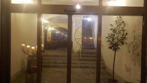A hotel entrance with a staircase leading to a second floor. There are candles on a table and a potted plant by the entrance. - Goldner Löwe (Stolpen)