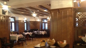 A restaurant with wooden paneling, multiple tables, and hanging lights. - Goldner Löwe (Stolpen)
