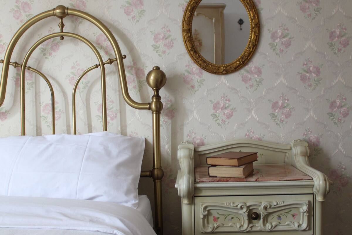 Un lit bien fait, avec une tête de lit, une commode à tiroirs et un miroir accroché au mur.