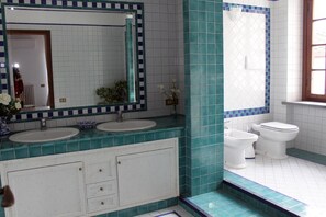 Une salle de bain avec deux lavabos, un grand miroir et des toilettes.
