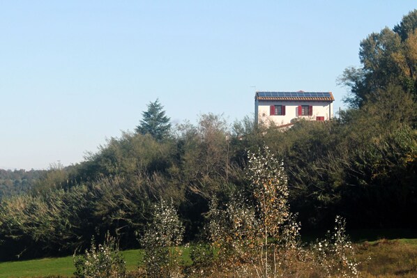 Ein Haus auf einem Hügel, bewölkter Himmel.