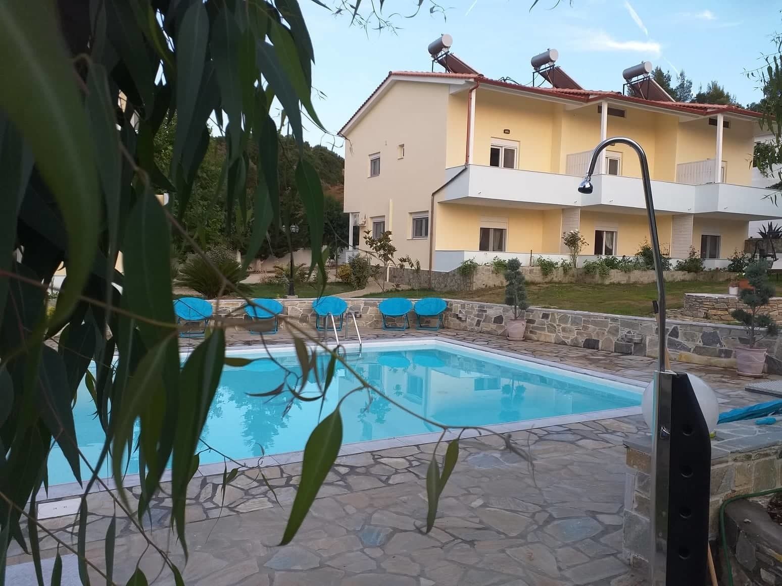 A swimming pool with stone tiles, surrounded by a stone wall and potted plants.