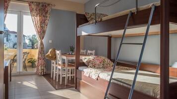 A bunk bed room with a desk and chair, a ladder, and a view of the outside.