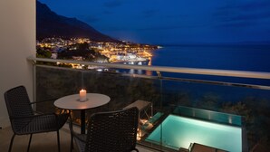 Un balcon avec une table et des chaises, donnant sur un paysage urbain et une piscine.