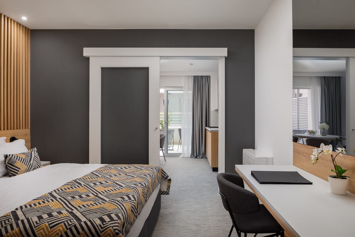 Ein modernes Hotelzimmer mit einem großen Bett, einem Schreibtisch und Blick auf einen Balkon.