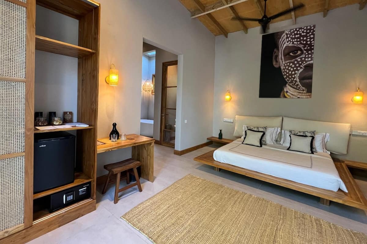 Ein Schlafzimmer mit einem Bett, Nachttischen, einem Schreibtisch mit Stuhl, einem Fernseher und einem Wandbild.