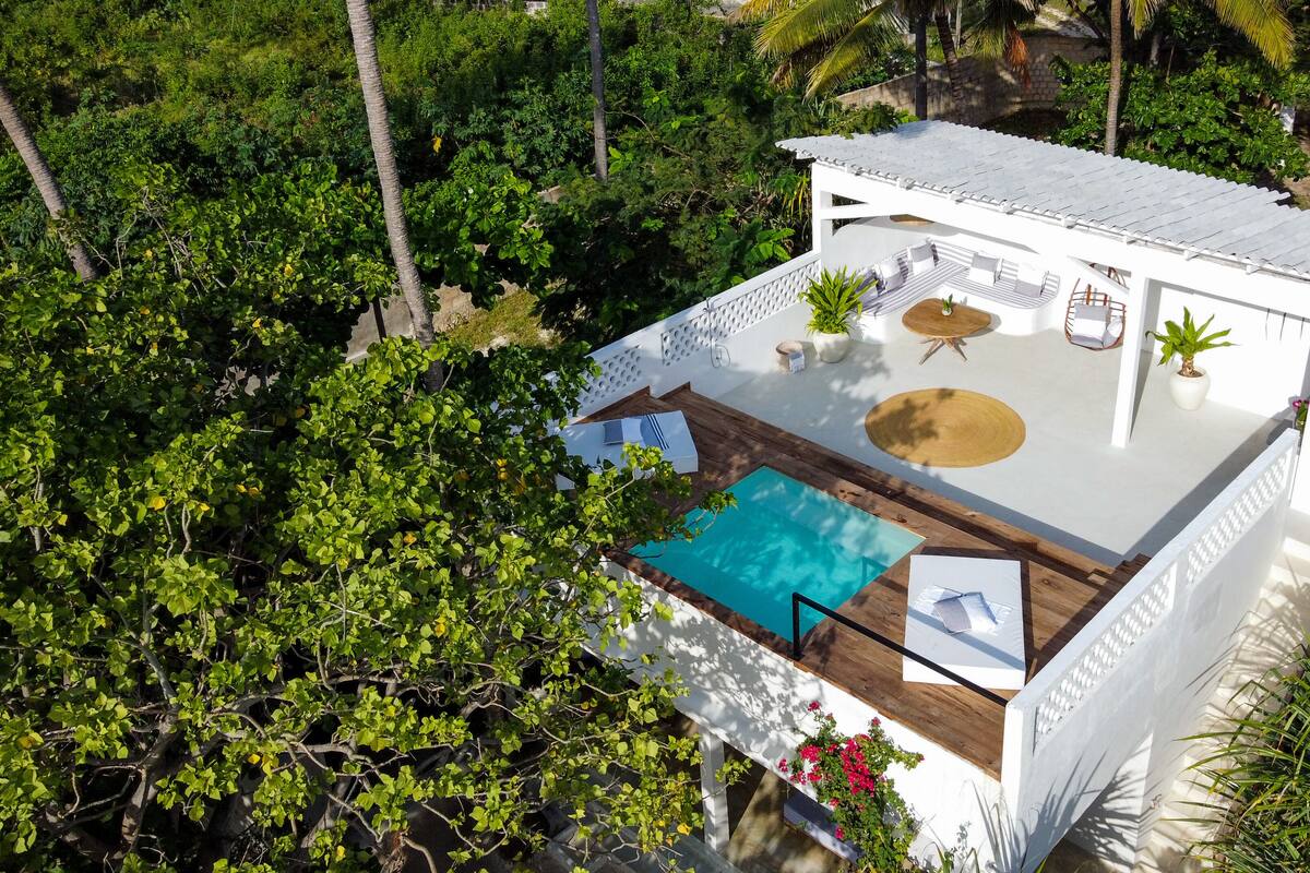 Eine moderne Villa mit Pool auf dem Dach, umgeben von üppiger Vegetation.